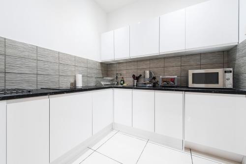 爱丁堡格罗夫纳公寓的白色的厨房配有白色的橱柜和微波炉