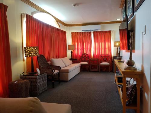 麦克坦Stay Amare Pacific Grand Magnolia的带沙发和红色窗帘的客厅