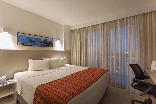马卡埃Ramada by Wyndham Macae Hotel & Suites的酒店客房设有床和窗户。