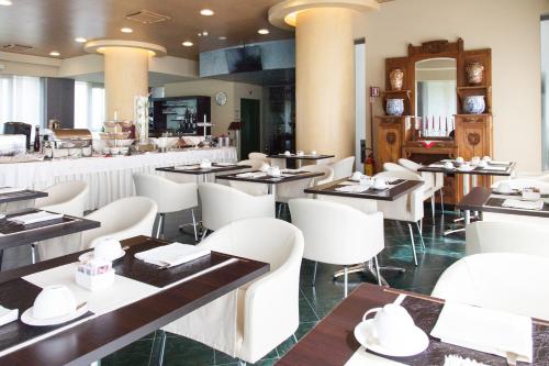 戈尔贡佐拉瑟纳特酒店的餐厅设有桌子、白色椅子和柜台