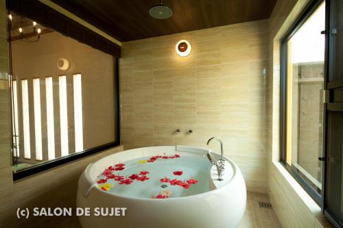 名户Bougain Terrace Resort Thi-chi House的浴室设有白色浴缸,内有红色的鲜花