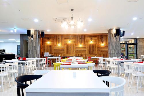 西归浦市Grandmillions Hotel Seogwipo的一间设有白色桌椅的用餐室