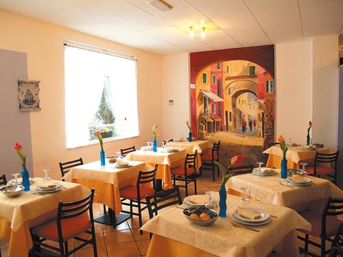 莱圭利亚阿德里安娜酒店的餐厅设有桌椅,墙上挂有绘画作品