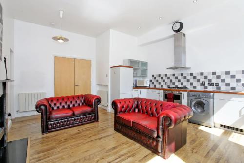 阿伯丁埃斯拜特市中心公寓酒店的一间带两张红色椅子的客厅和一间厨房