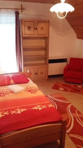 蒂萨菲赖德Osho Vendégház的一间卧室配有一张床和一张红色椅子
