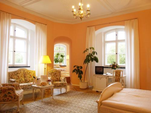 格洛韦施比克城堡酒店的客厅拥有橙色的墙壁和一张床及椅子
