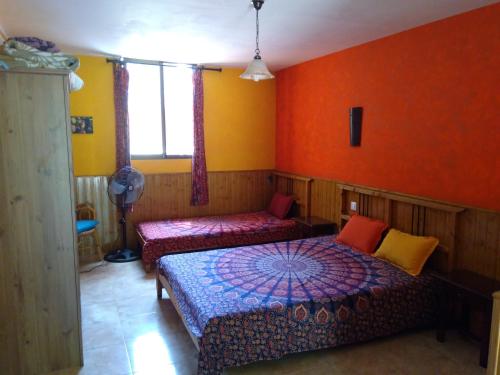 阿雷纳斯德圣佩德罗Casa Rural Las Gesillas的一间卧室设有两张床,拥有橙色的墙壁。
