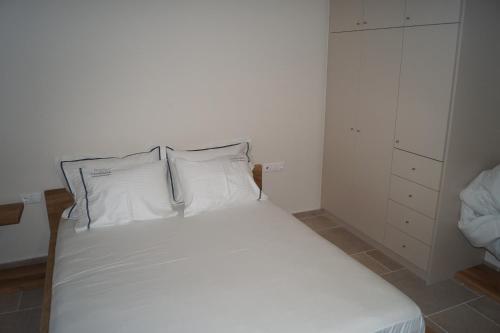 KariáLagkada Suites的卧室内的一张带两个枕头的白色床