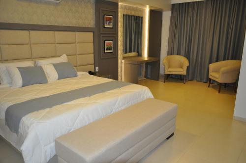 Marechal Cândido RondonHospedare Hotel的酒店客房带一张大床和椅子