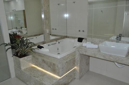 Marechal Cândido RondonHospedare Hotel的带浴缸、两个盥洗盆和镜子的浴室