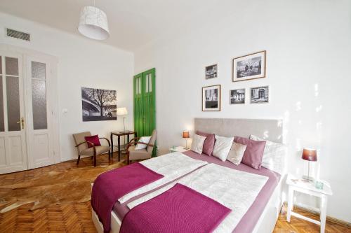 布达佩斯绿门家庭公寓的一间卧室配有一张大床,铺有紫色和白色的床单。