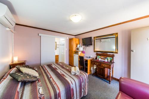 金格罗伊金格罗伊乡村汽车旅馆的配有一张床和一张书桌的酒店客房