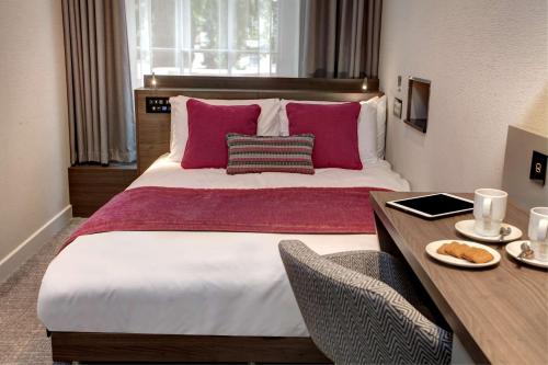 伦敦Best Western Plus Delmere Hotel的卧室配有一张带粉红色枕头的大床