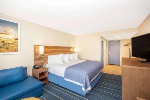 科尔尼Days Inn & Suites by Wyndham Kearney NE的配有一张床和一台平面电视的酒店客房