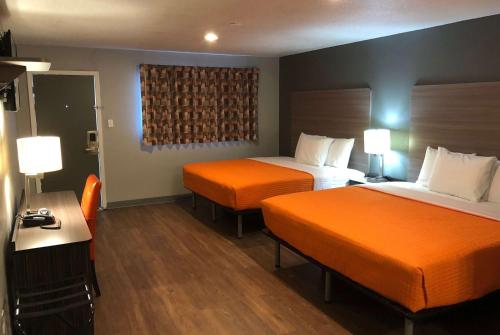 索诺拉Super 8 by Wyndham Sonora的酒店客房带两张带橙色床单的床