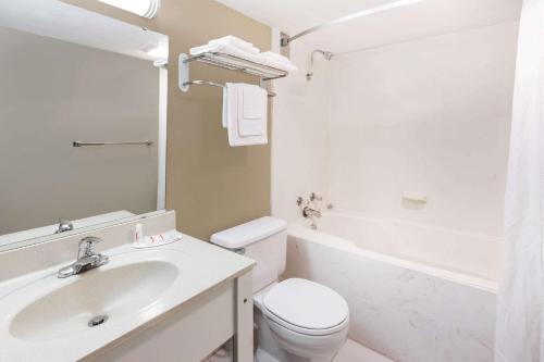 哈里森哈里森速8酒店的白色的浴室设有卫生间和水槽。