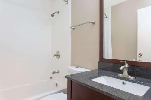 哥伦布哥伦布机场速8酒店的浴室配有盥洗盆、镜子和浴缸