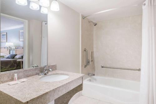 沃尔顿堡滩沃尔顿堡滩速8酒店的一间带水槽、浴缸和镜子的浴室