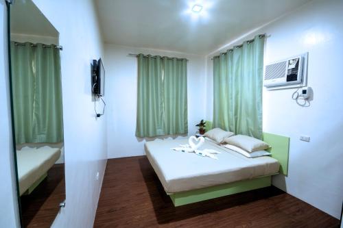 杜马格特Sulit Budget Hotel near Dgte Airport Citimall的小房间,配有床和绿色窗帘