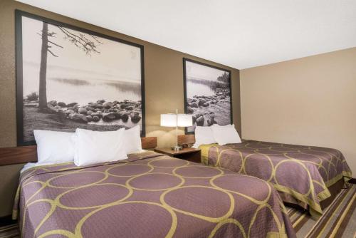 圣克劳德圣克劳德速8酒店的酒店客房设有两张床,墙上挂着一张照片。