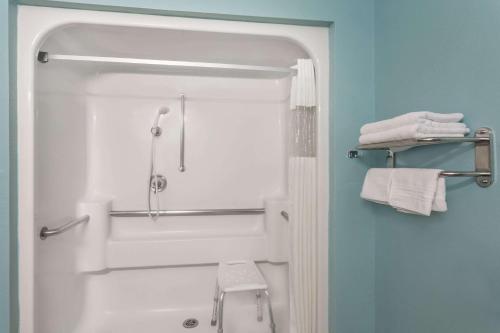 雪松城雪松城速8酒店的带淋浴、卫生间和毛巾的浴室