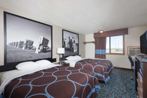 图克姆卡里Super 8 by Wyndham Tucumcari的酒店客房设有两张床和大屏幕
