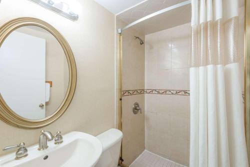 罗基希尔Howard Johnson by Wyndham Rocky Hill的浴室配有盥洗盆和带镜子的淋浴