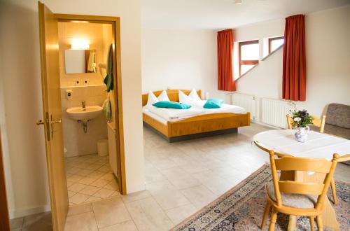 博登海姆Hotel Janssen的酒店客房设有一张床铺、一张桌子和一间浴室。