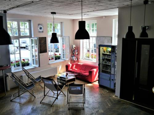 格但斯克La Guitarra Hostel Gdańsk的客厅配有红色的沙发和椅子