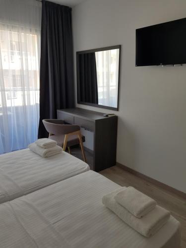 拉纳卡Les Palmiers Petrou Apartments的一间卧室配有两张床、一张桌子和一台电视。