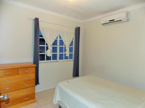 帕罗卡02 - CASA praia PINHEIRA pousada的一间卧室配有一张床、一个梳妆台和一扇窗户。