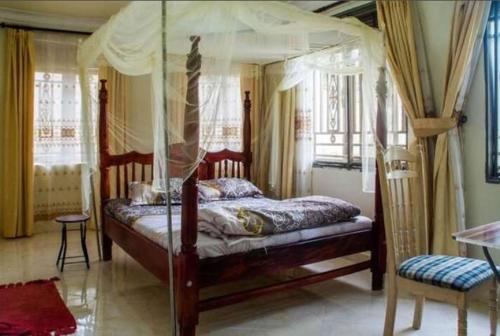 姆巴拉拉Palace Hotel的一间卧室配有一张天蓬床和一把椅子