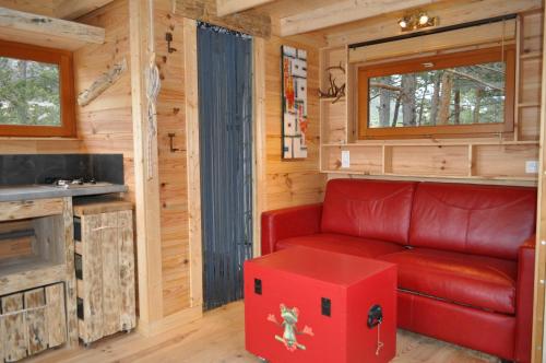 Valderoure卡巴内德格纳泽莱斯假日公园的客厅配有红色沙发和红色的盒子