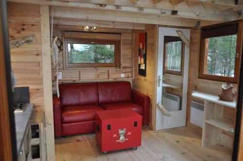 Valderoure卡巴内德格纳泽莱斯假日公园的一间位于小房子内的客厅,客厅里配有红色沙发