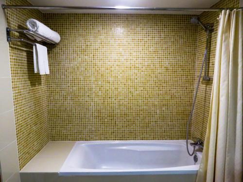 甘榜杰鲁登思达酒店的带浴缸的浴室和绿色瓷砖墙