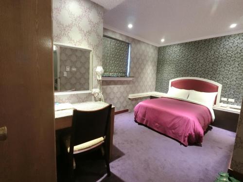 台北一等好旅店的卧室配有粉红色的床、书桌和书桌。