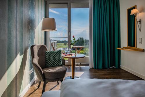 巴特瓦尔德塞Waldsee Golf-Resort的酒店客房设有椅子、桌子和窗户。