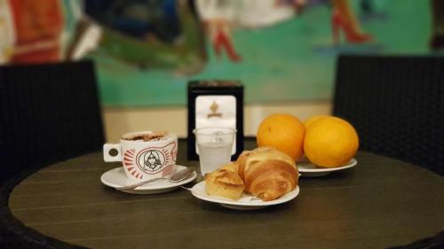 曼杜里亚B&B La Sinagoga的一张桌子,上面放着两杯咖啡,羊角面包和橙子