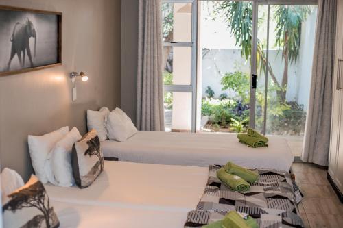奥奇瓦龙戈Out of Africa Guesthouse的酒店客房设有两张床和窗户。