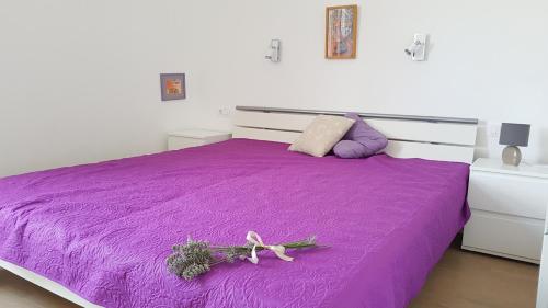 木洛希尼Apartman Di的紫色的床,上面有花