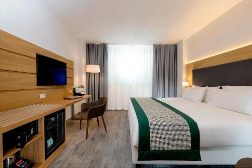 那不勒斯那不勒斯假日酒店的酒店客房配有一张床和一张书桌及一台电视