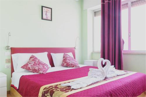锡拉库扎华夏 仙客来家庭宾馆的一间卧室配有粉红色的床,上面有毛巾