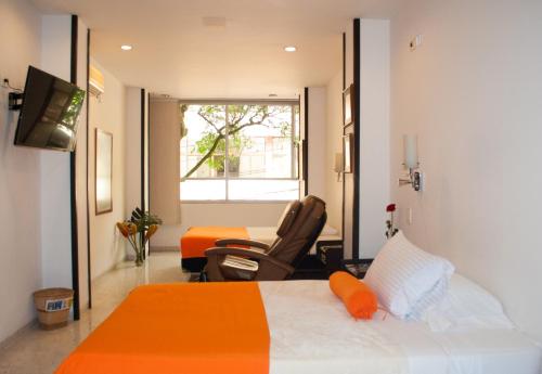 卡利Hotel Casa Santa Monica Norte的卧室配有床、椅子和窗户。