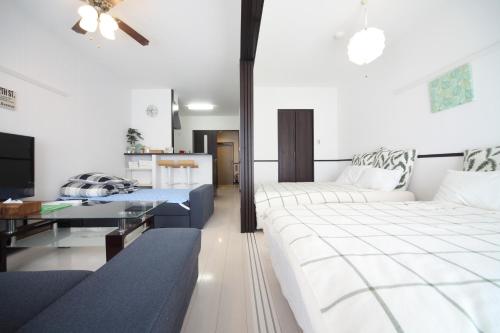 糸满EX Itoman Apartment 802的一间卧室配有两张床、一张桌子和一张沙发