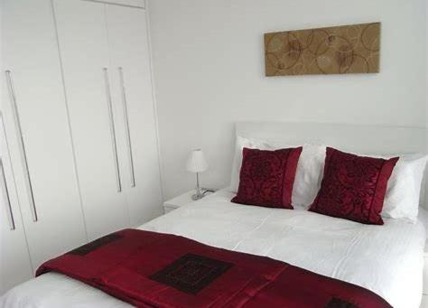 利兹Serviced Apartments Leeds的卧室内的白色床和红色枕头
