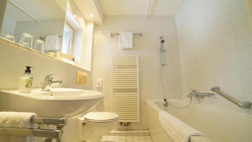 施利尔塞施利尔斯伯格阿尔姆酒店的浴室配有盥洗盆、卫生间和浴缸。
