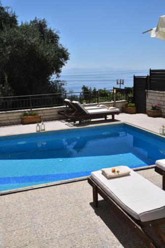 帕拉马Achillion Luxury Corfu Villa的一个带桌椅的蓝色游泳池,并享有海景