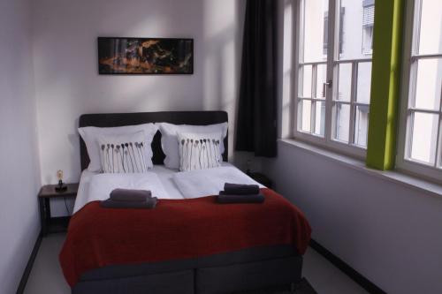莱比锡思乐迪奥公寓的一间卧室配有一张带红色毯子的床和两个窗户。