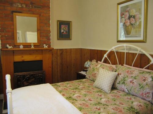 EvandaleArendon Cottage的一间卧室配有一张床、一个壁炉和一个镜子