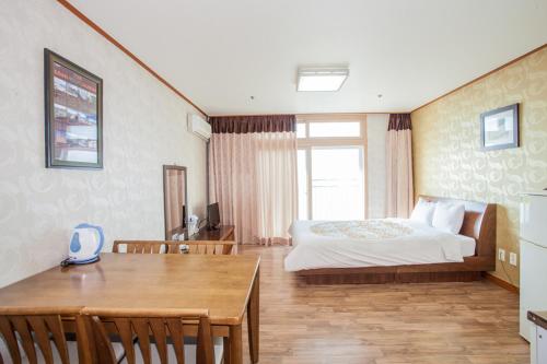 济州市Jeju Ilsung Beach Condo的一间卧室配有一张床铺和一张桌子,还有一间用餐室